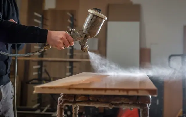 Custom restoration service in the Dubai showing a craftsman spray finishing a wooden surface, restoring furniture with precision coating and professional woodwork techniques